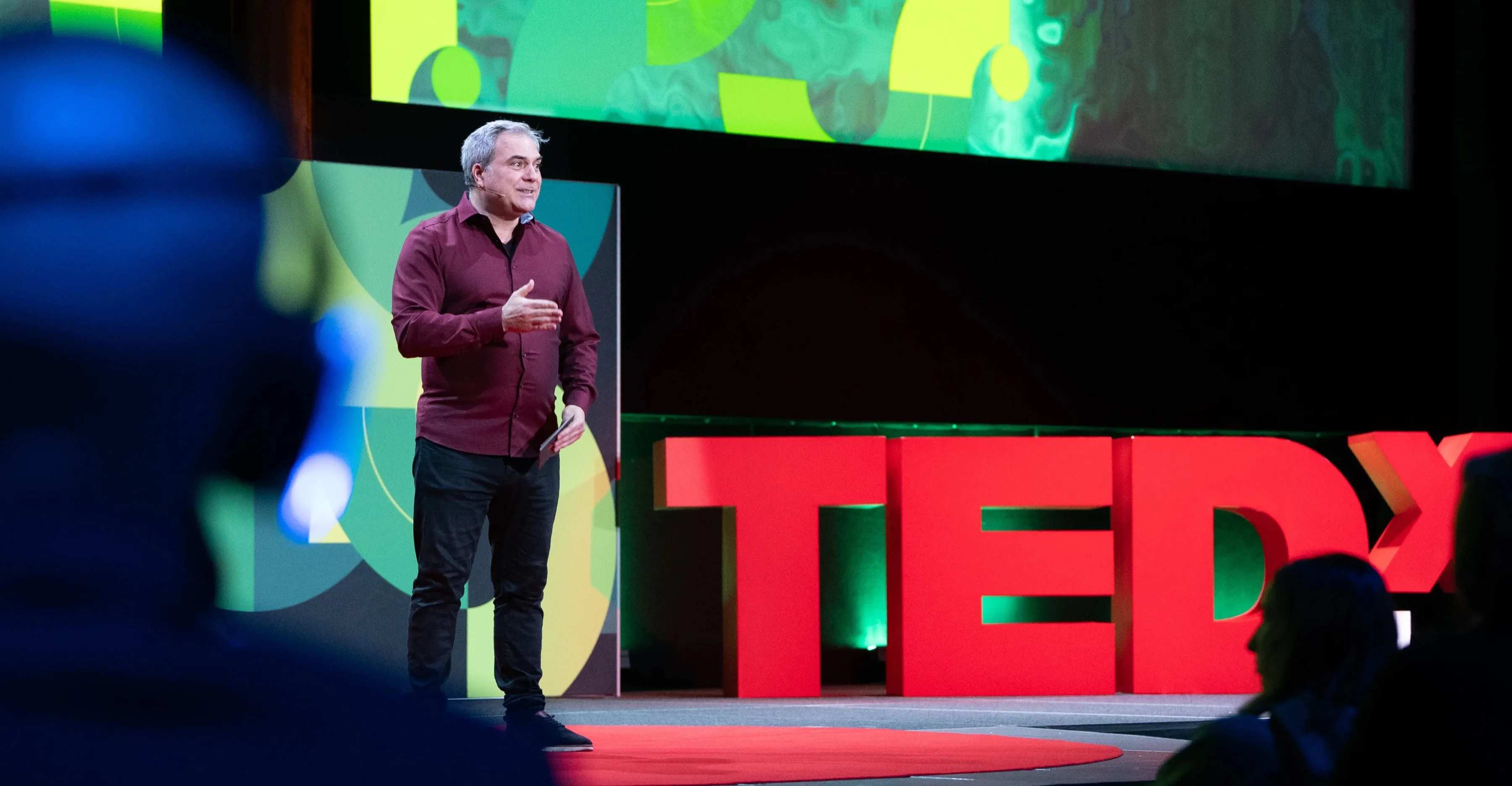 TEDx Lausanne 2025 stage — speaker under lights in front of a full audience